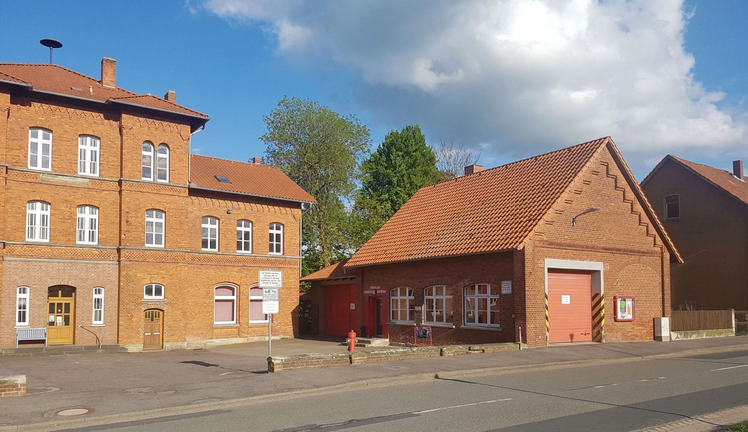 Das frühere Feuerwehrhaus: Backsteinbau mit roten Toren neben dem ehemaligen Rathaus